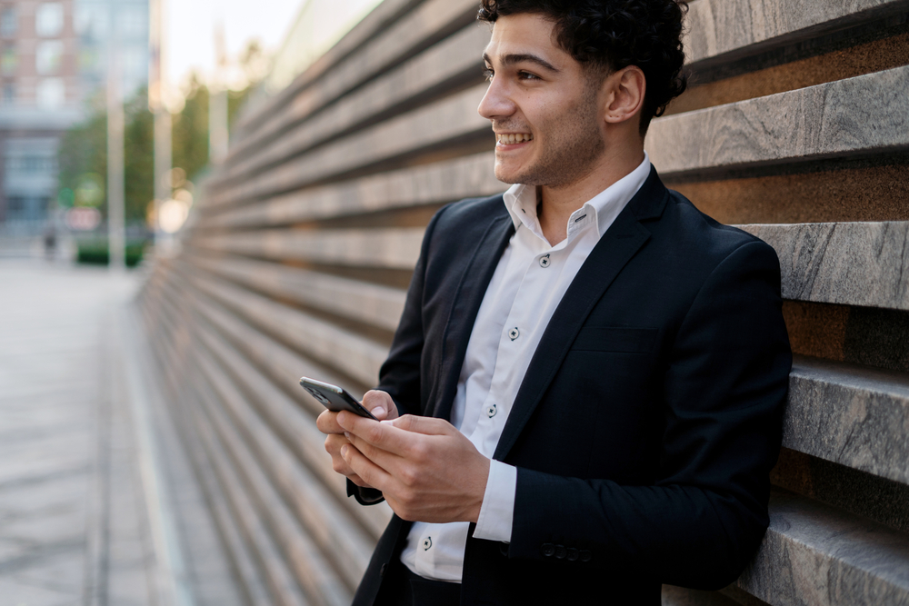 Young man looks up from phone optimistic about retirement savings