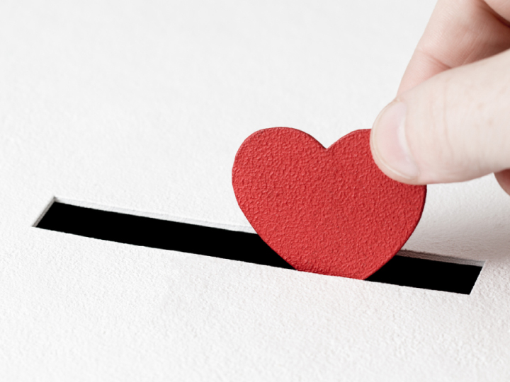 a person is putting a red heart on a piece of paper