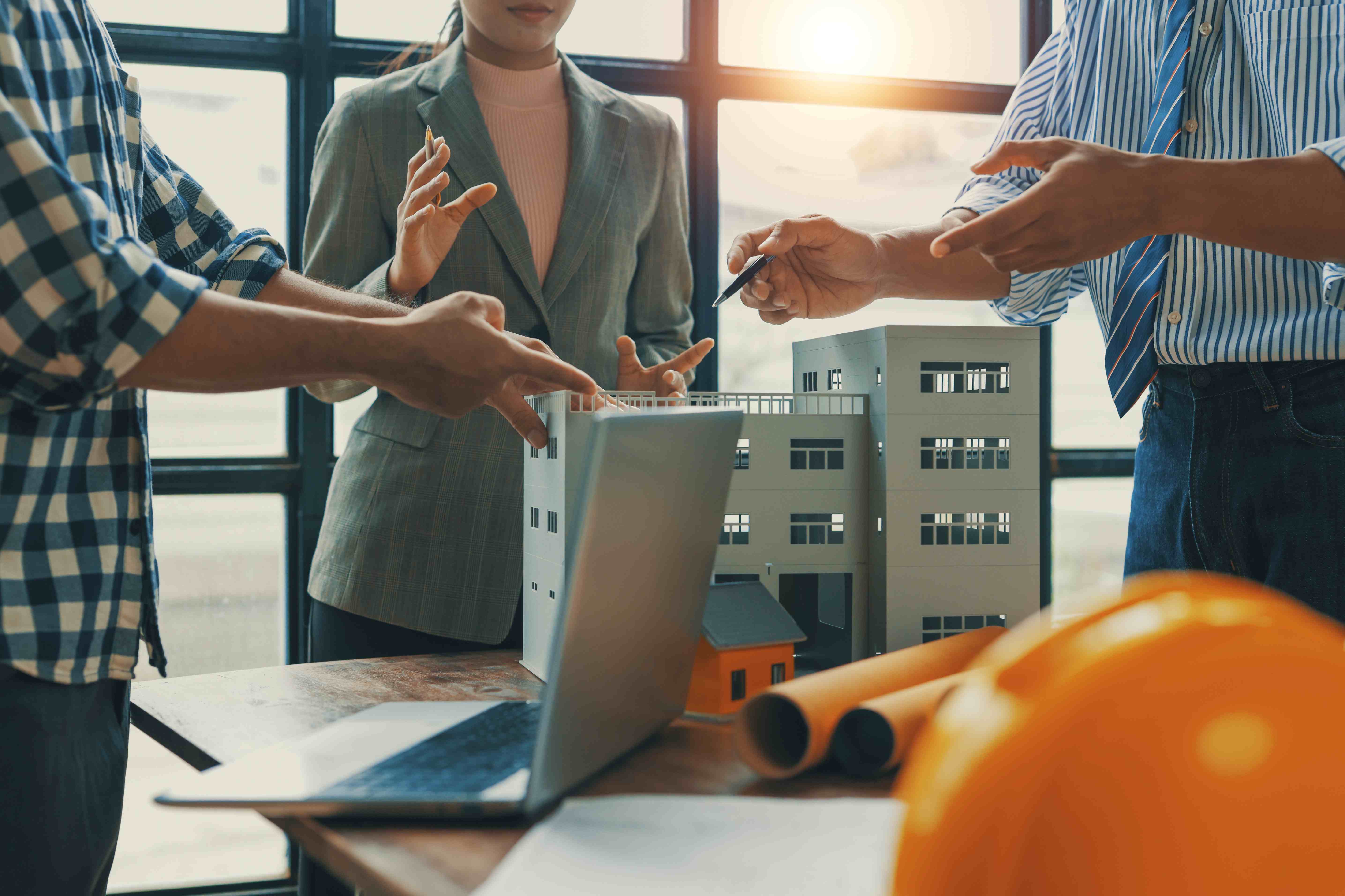 Financing Commercial Purchase - Three colleagues review laptop and commercial building model