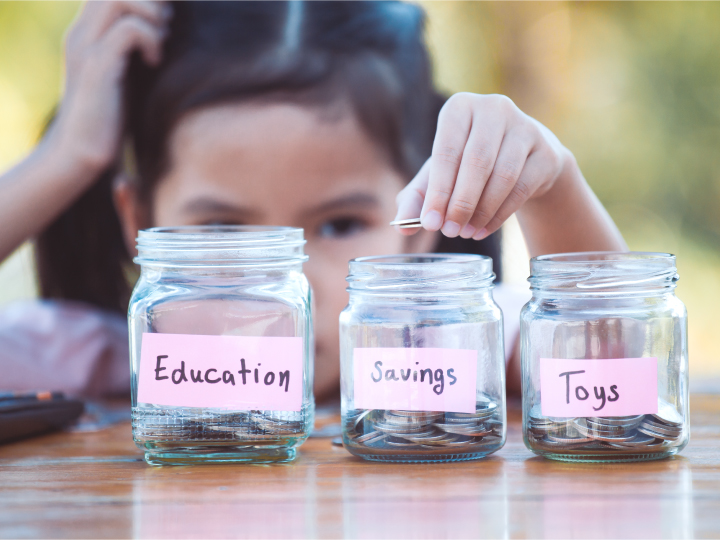 Child placing coin into savings jar