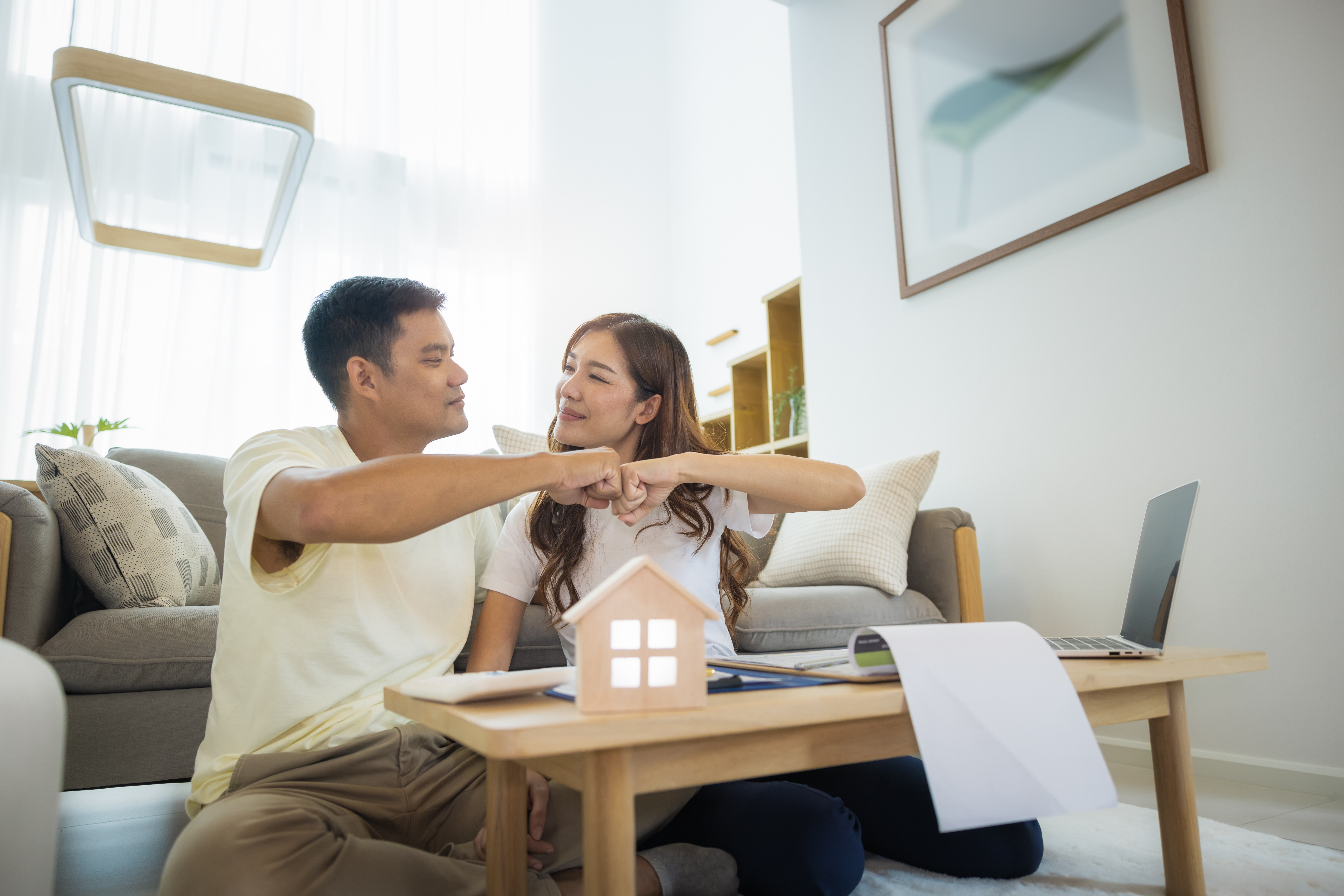 Couple home searching fist bump at coffee table