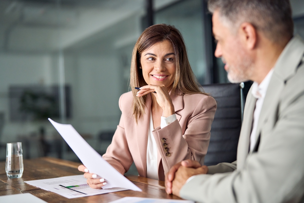 a women and a man sitting at table looking at piece of paper