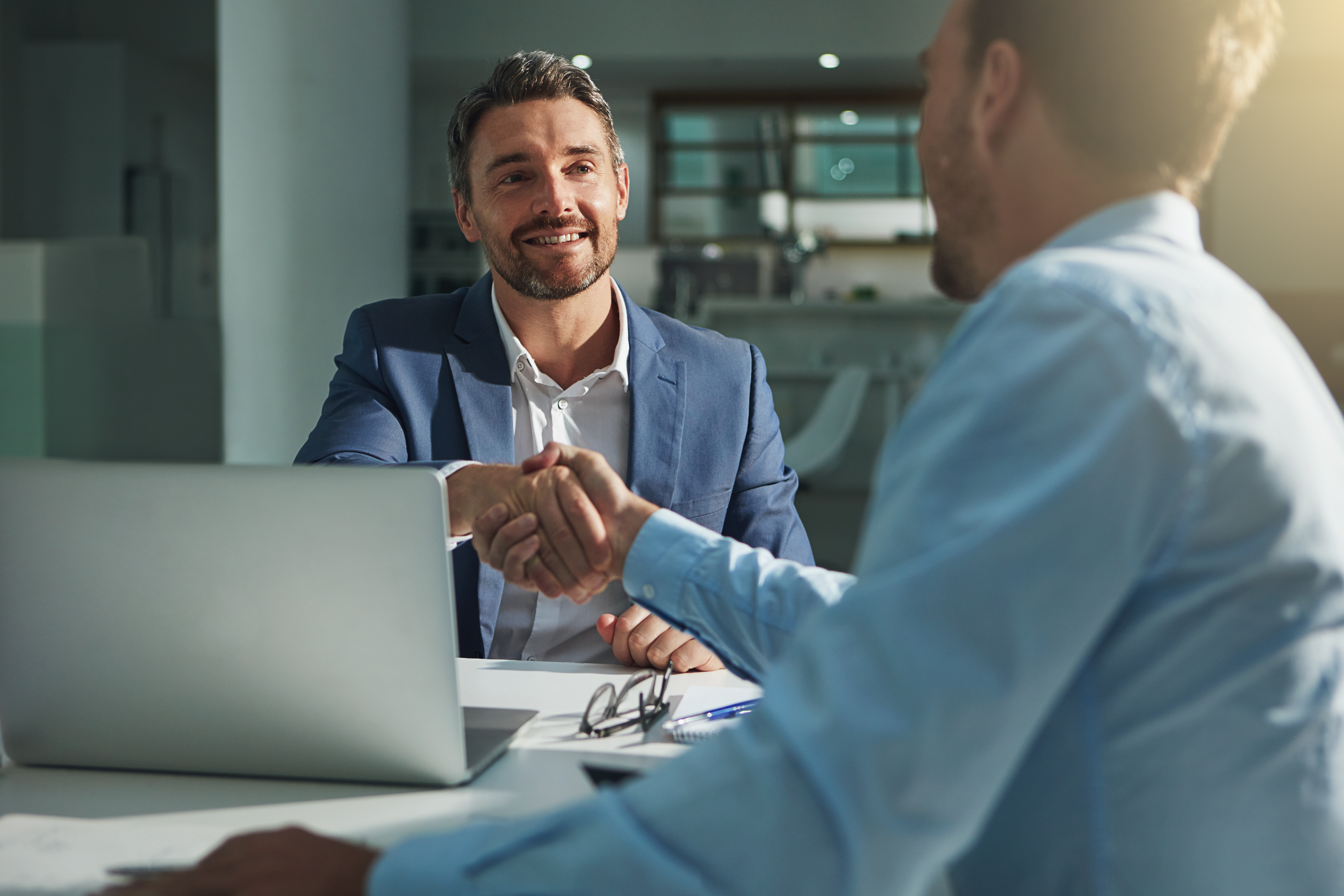 Banker and client shaking hands at desk