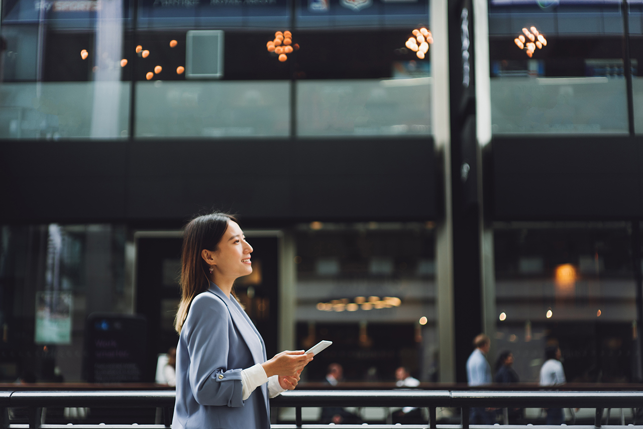 Woman standing in urban shopping center, looking at phone