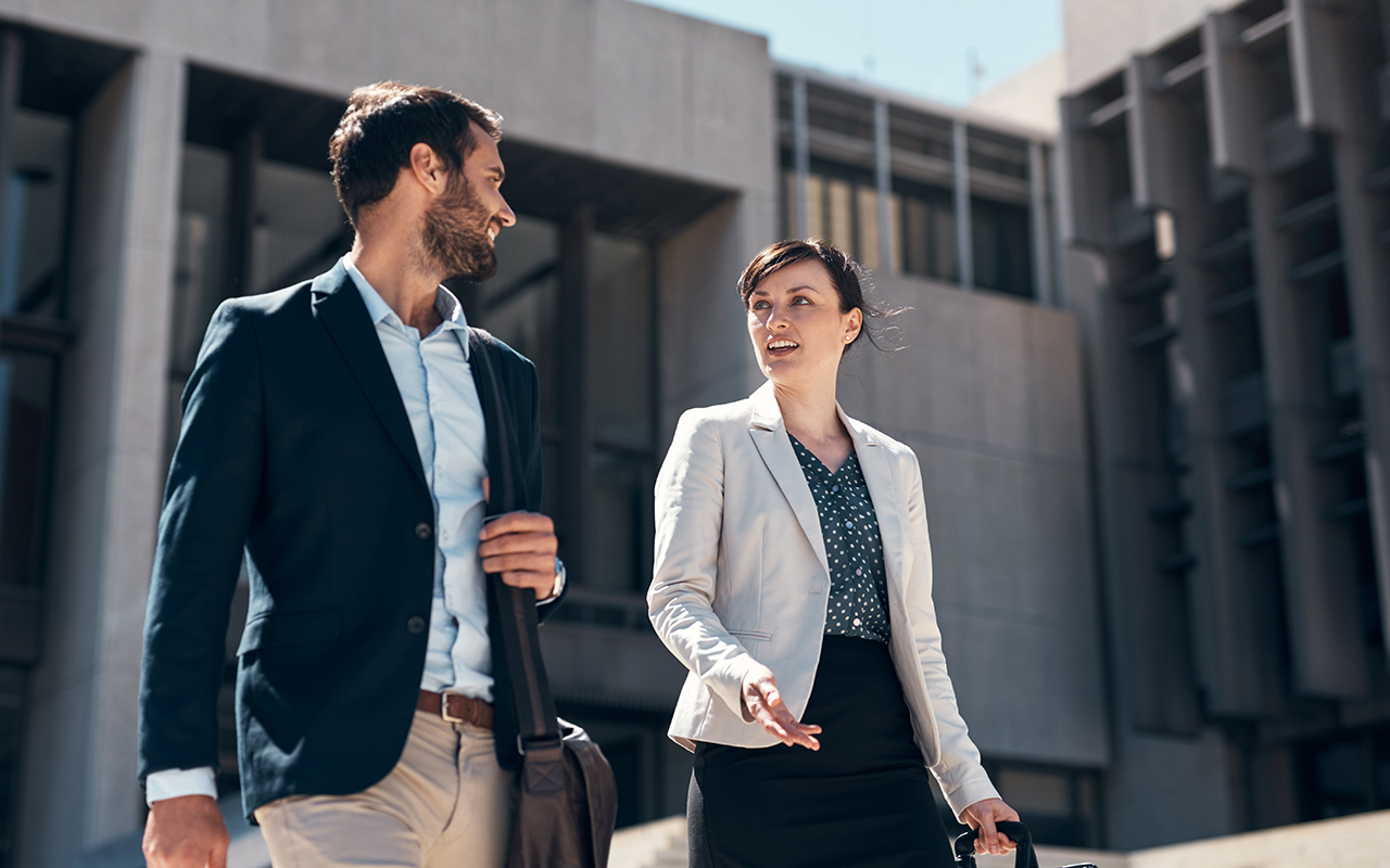 Business professional man and woman walking together in a modern city