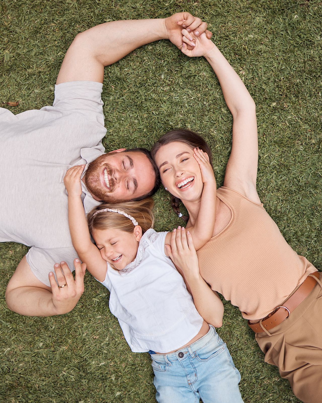 Family of four relaxing on grass outdoors, smiling together
