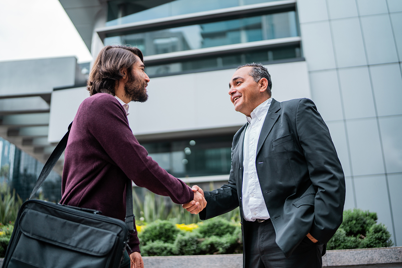 two men shaking hands outside a business building