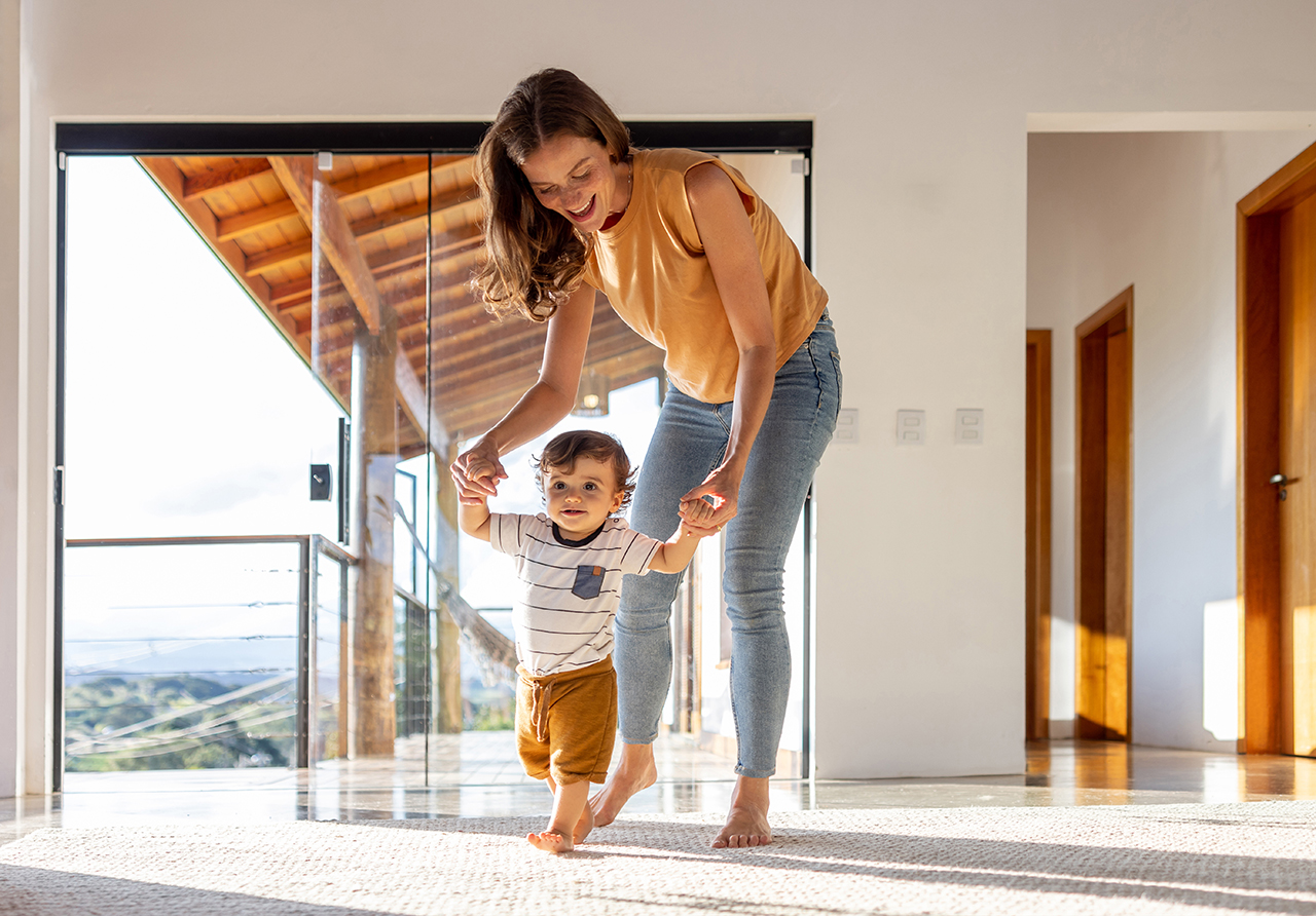 Woman carrying a child while walking through a home’s open doorway