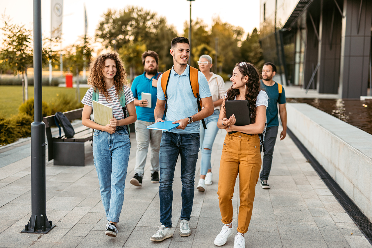 Group of  people walking outside in the city, carrying books and bags