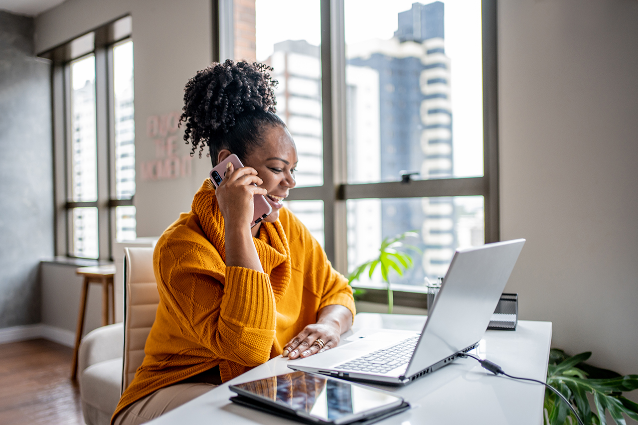 Woman working at a laptop in a modern home office, smiling and focused