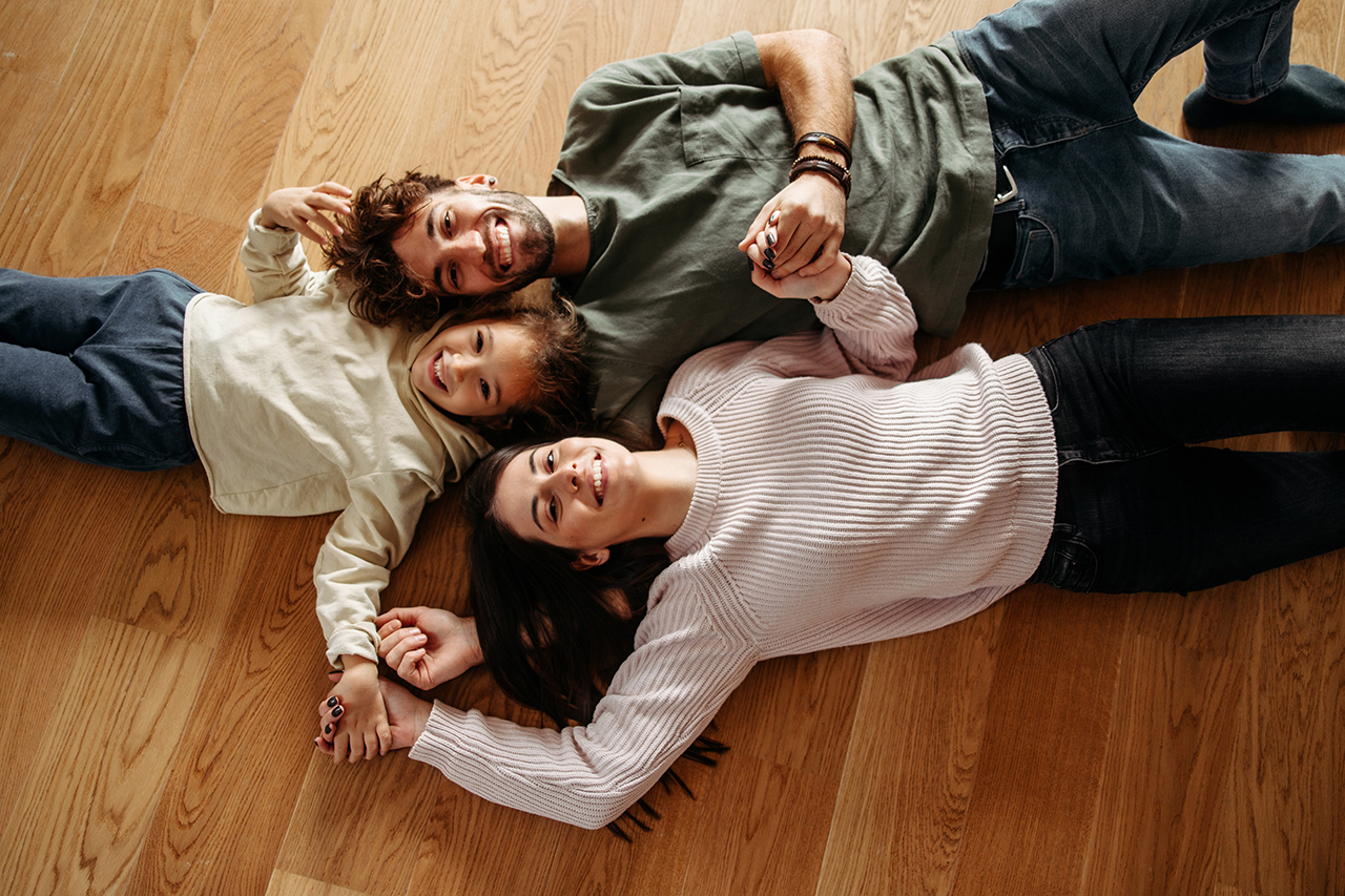 family lying on the floor together, laughing and playing
