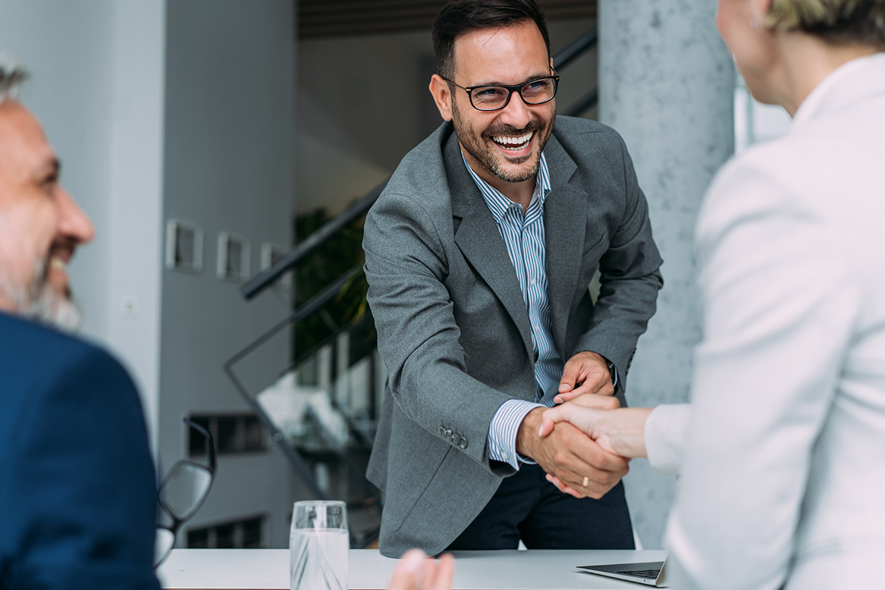 Business professional smiling while shaking hands in a meeting