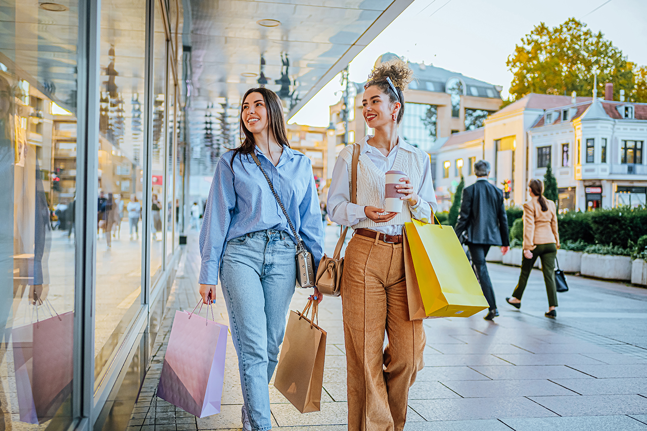 Young woman walking down the street, smiling, and carrying shopping bags