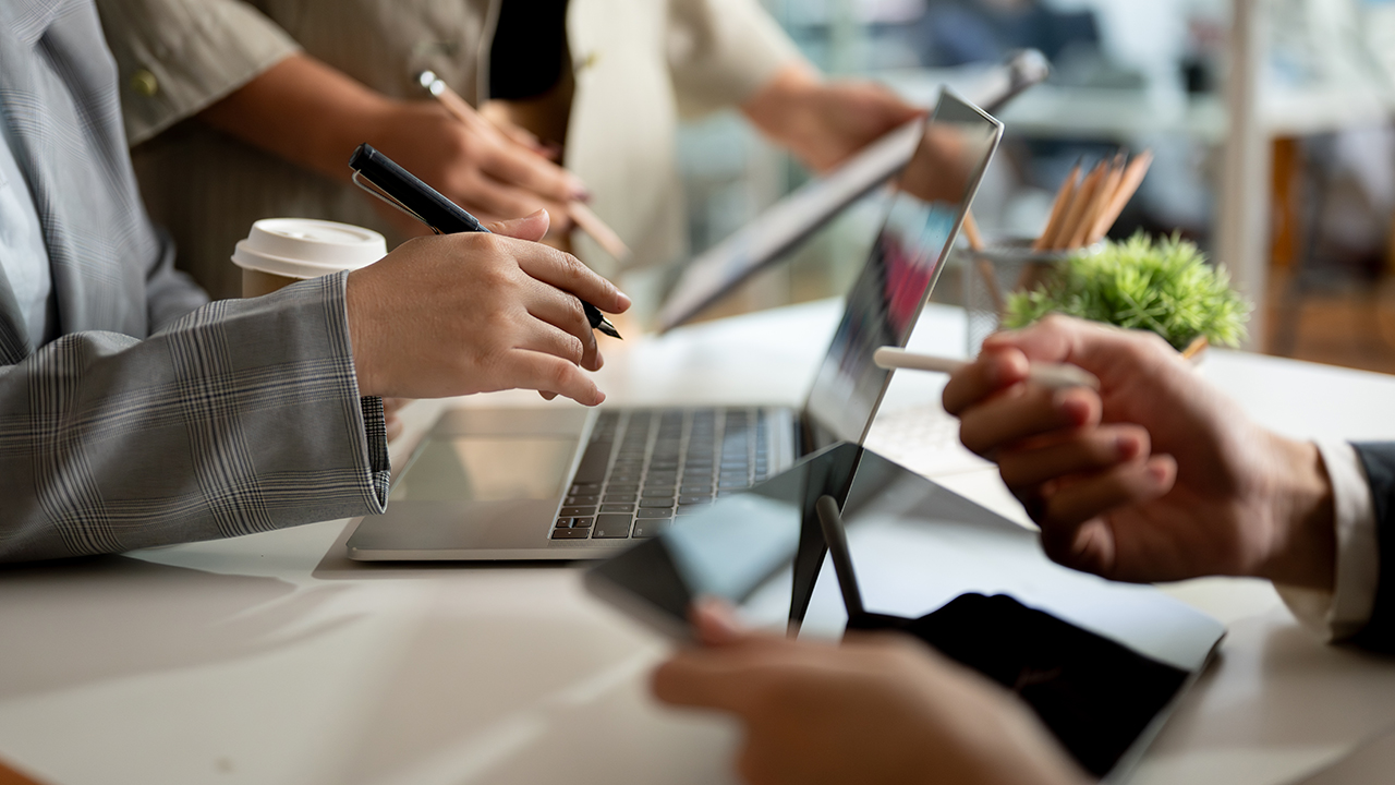 Close-up of hands typing on a laptop while holding a coffee cup