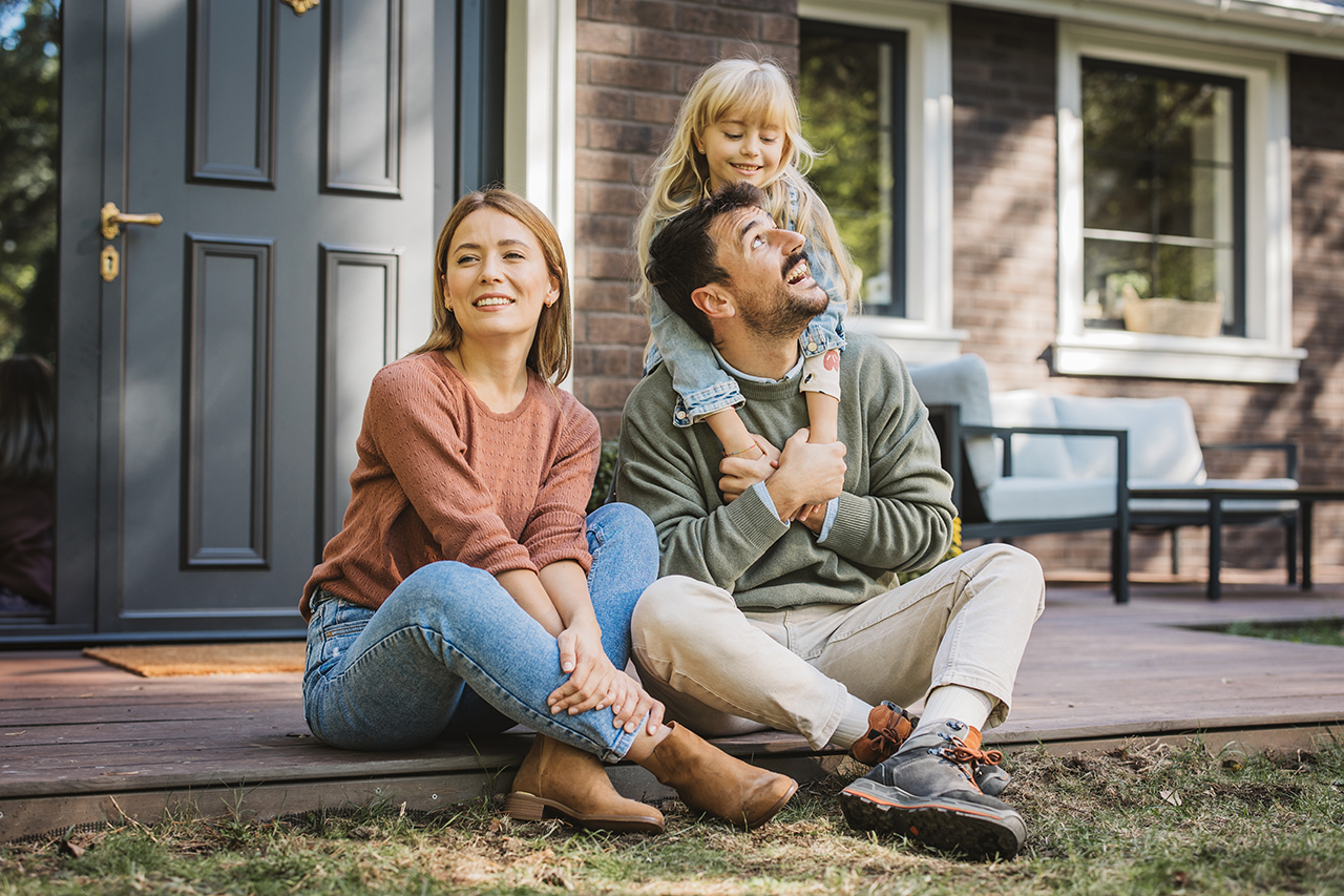 Family playing together in the yard, man and woman laughing and watching their children play soccer
