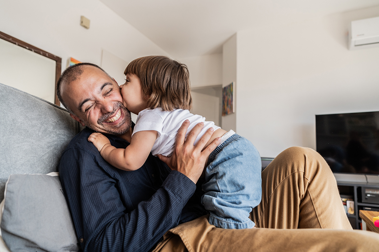 Man and child smiling and sharing a moment, father holding the child