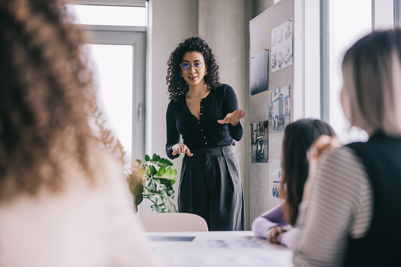 women speaking to a group in meeting room
