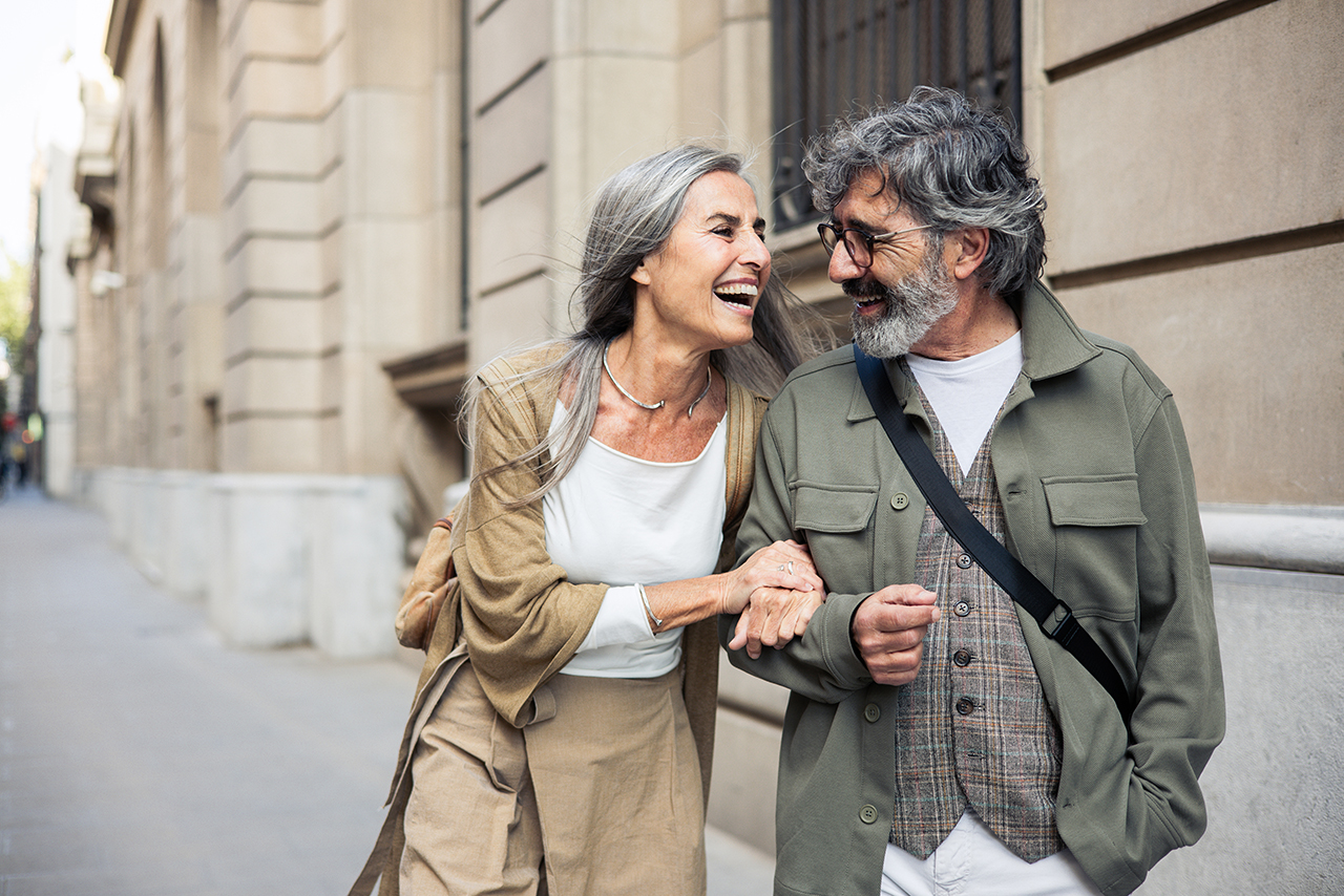 Elderly couple walking hand in hand down the street, enjoying each other’s company