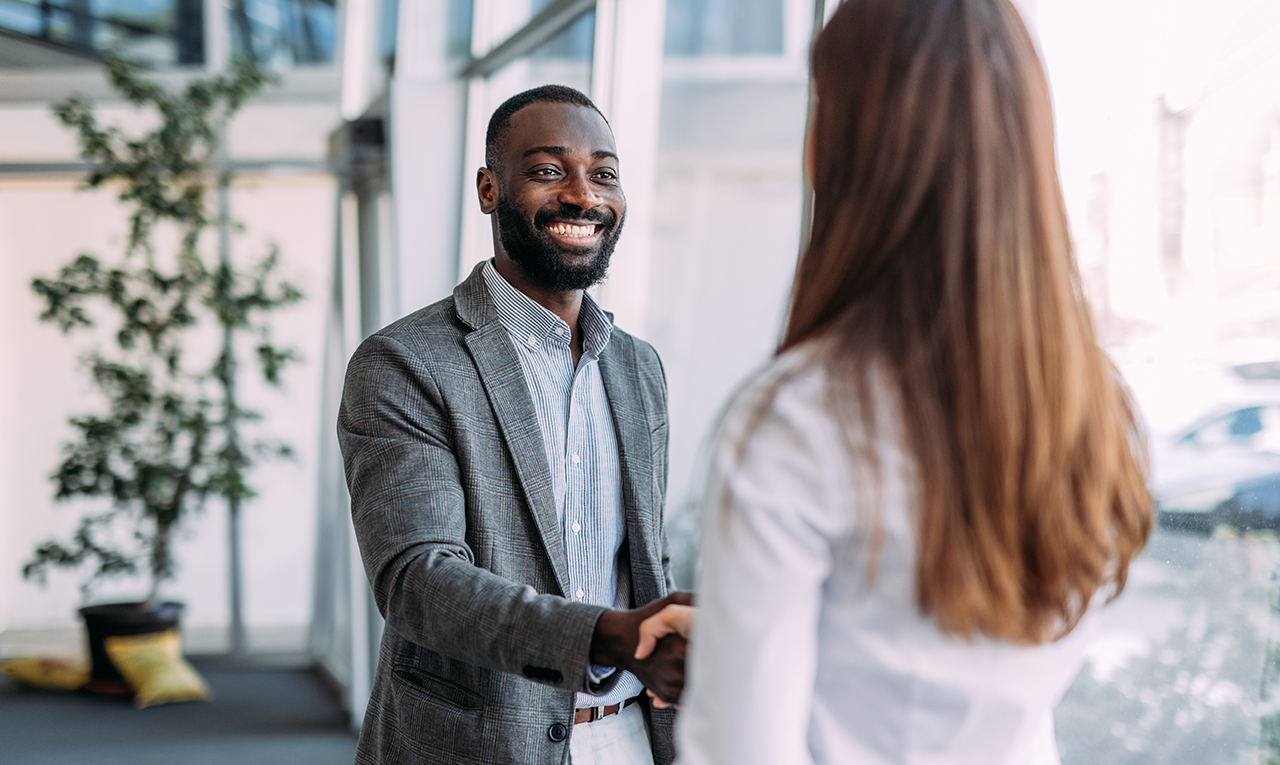 Man and woman shaking hands in a business setting, smiling