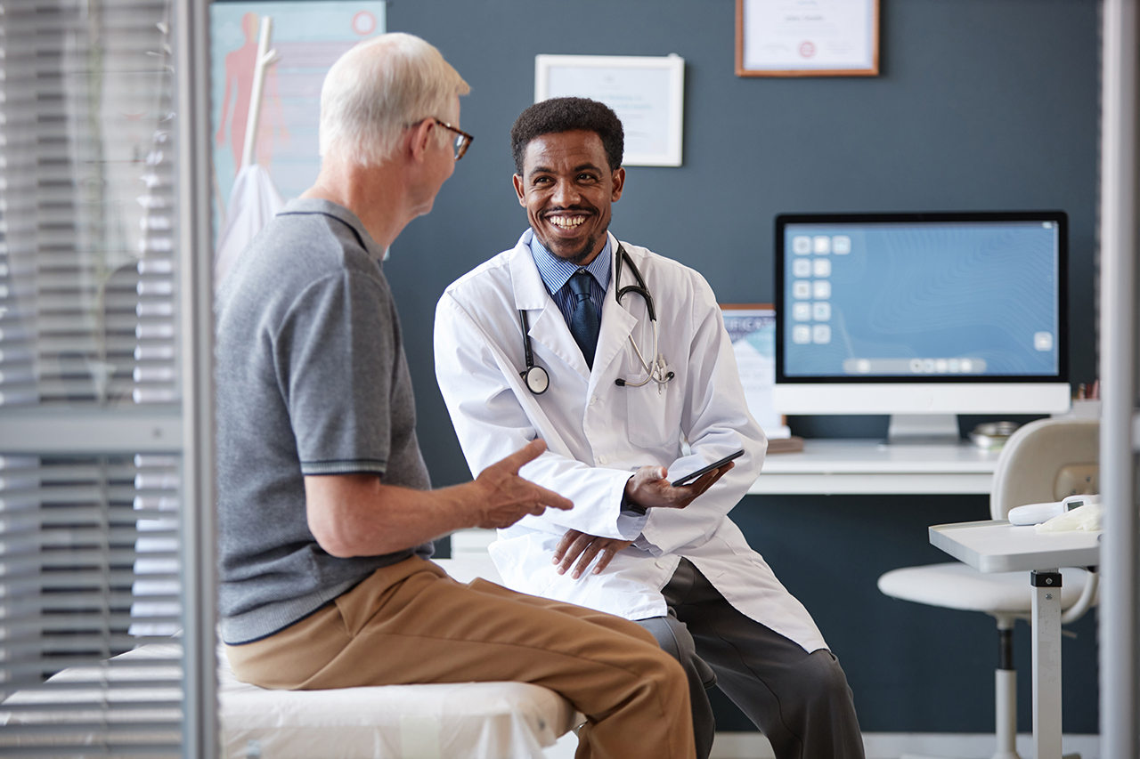 Doctor sitting with an elderly patient in an office, talking and discussing