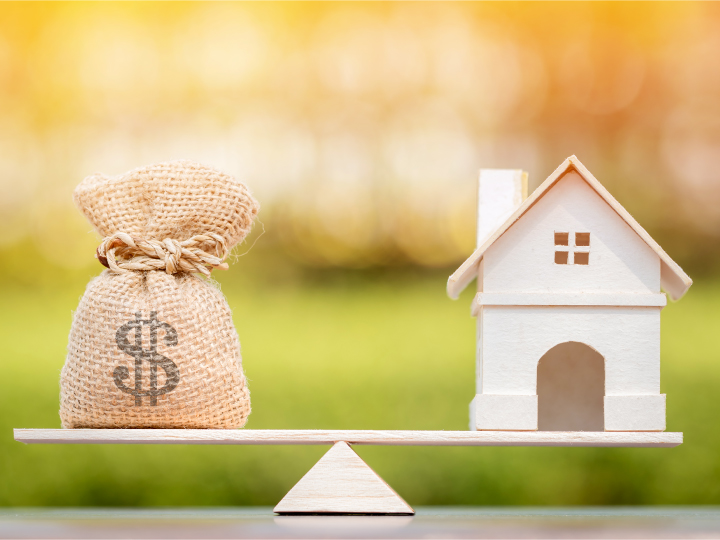 Money bag and house on a seesaw