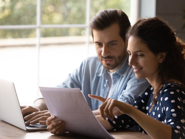 White couple reviewing important documents in front of a laptop
