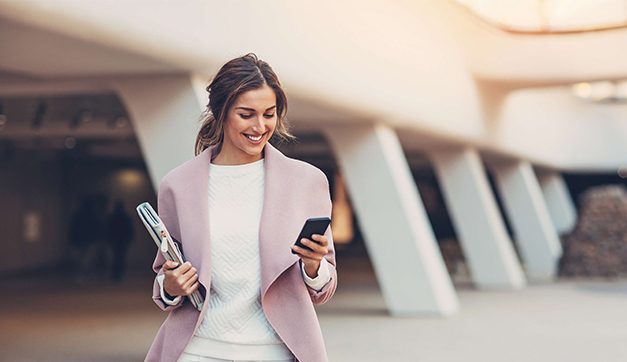 A woman walking and looking at private banking services on her mobile phone – Kearny Bank