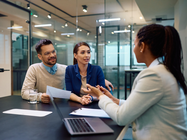 Young Caucasian couple talking to African American financial advisor